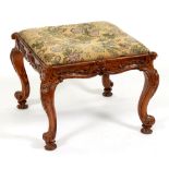 A Victorian carved walnut stool, with woolwork seat, 45cm h; 59cm w Minor shrinkage cracks to frame,