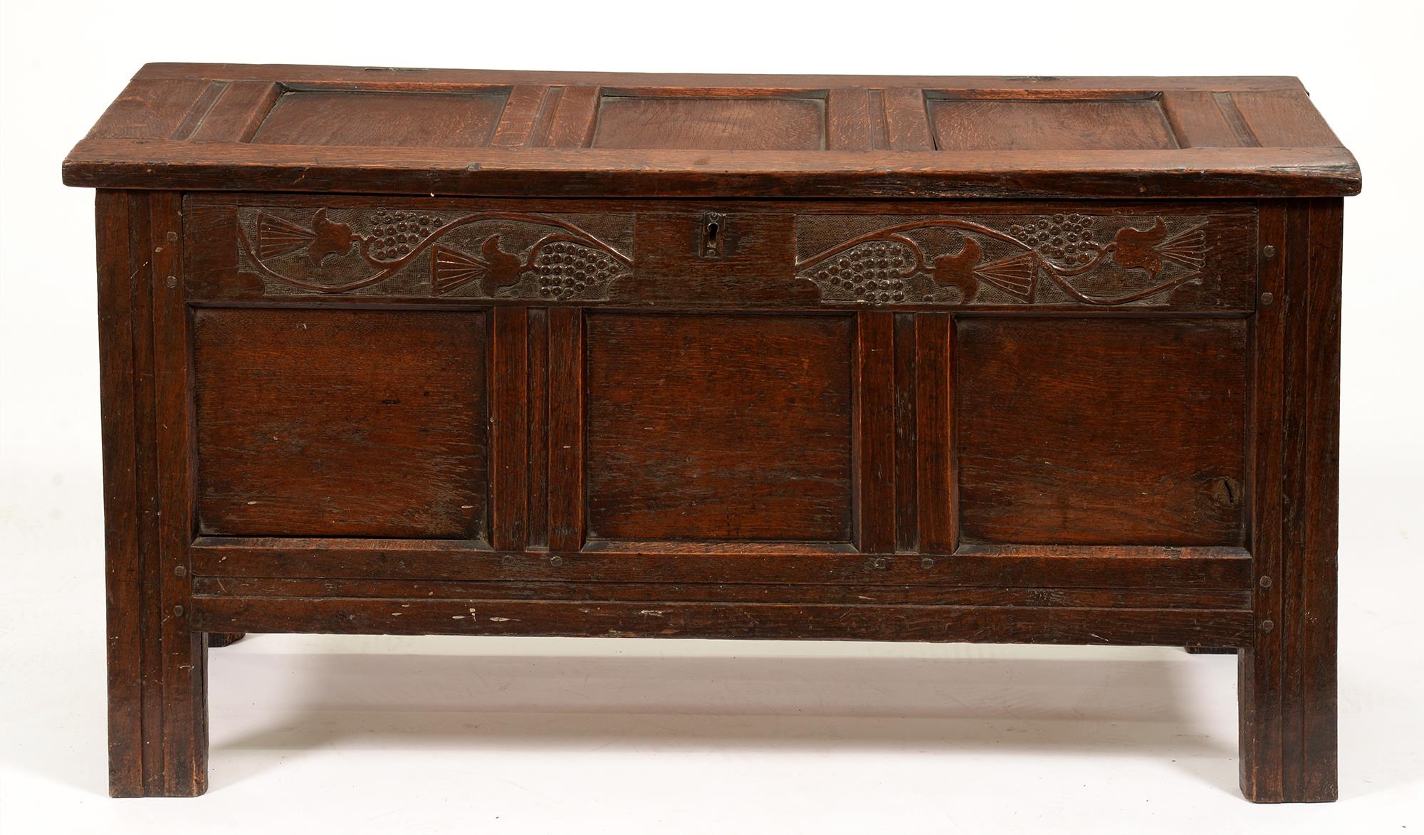 A late 17th or early 18th c panelled oak blanket box, the front top rail carved with thistles, the