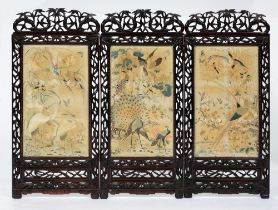 A Chinese carved and stained hardwood three-fold screen, early 20th c, the silk and needlework