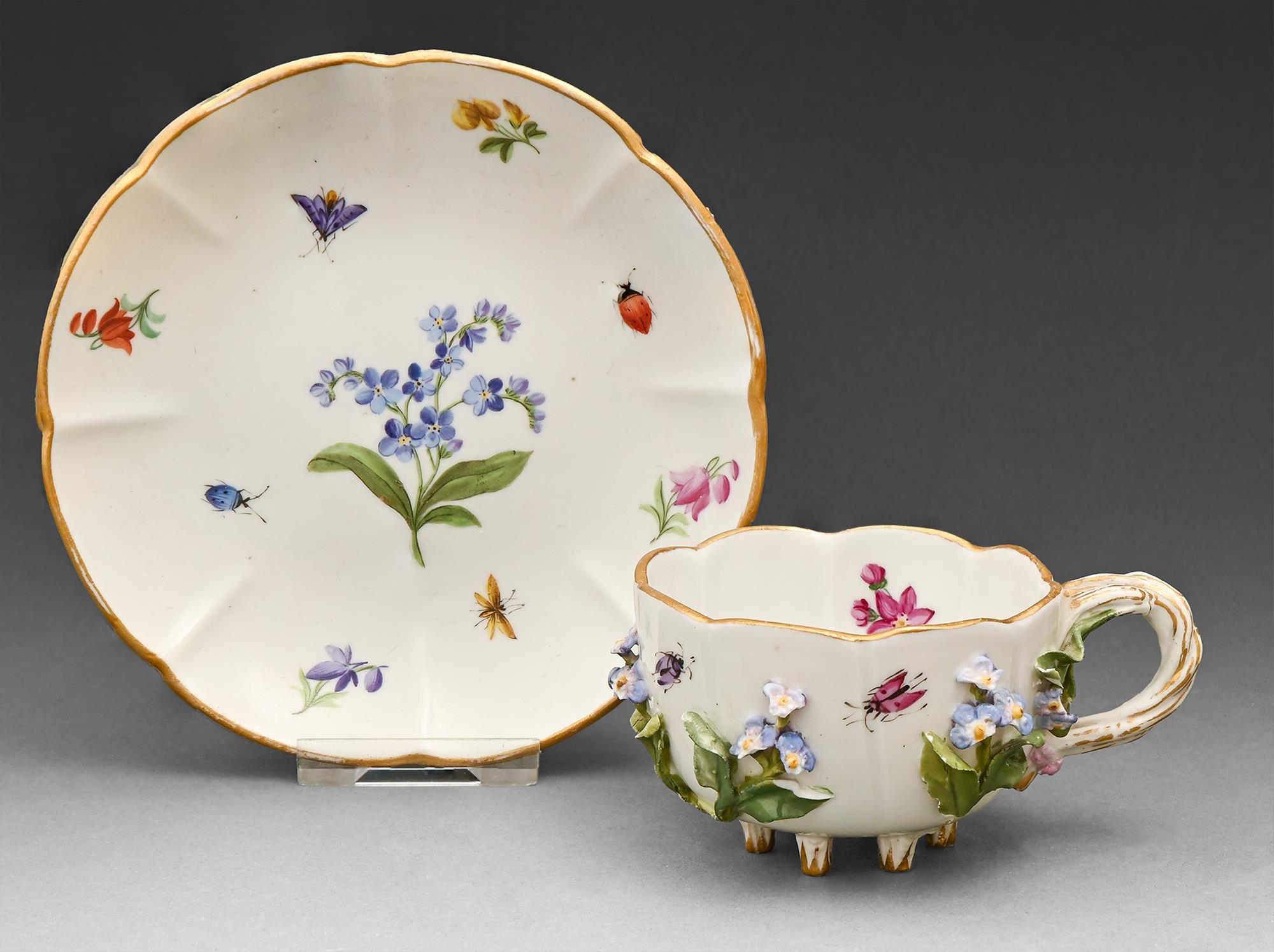 A Meissen floral encrusted cup and saucer, late 19th c, with entwined handle and painted with