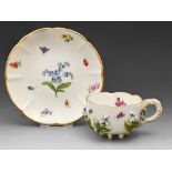 A Meissen floral encrusted cup and saucer, late 19th c, with entwined handle and painted with