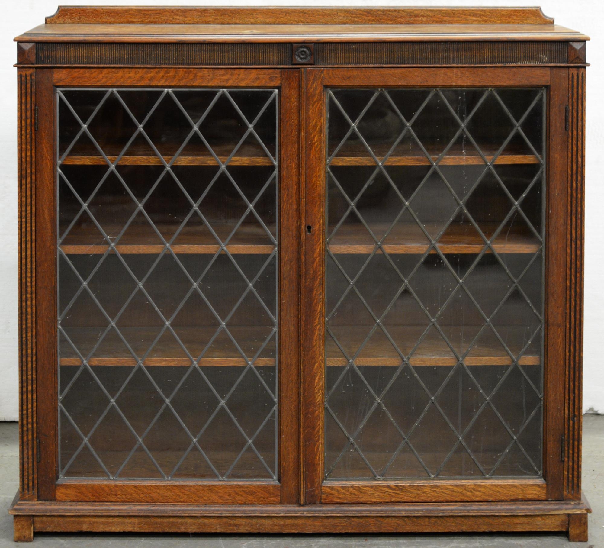 An oak bookcase, enclosed by a pair of leaded glass doors