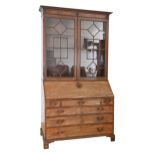 A George III mahogany bureau bookcase, the upper part with glazed doors, the cornice applied with