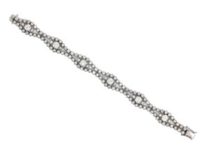 A diamond bracelet, designed as a swelling, wavy ribbon with larger round brilliant cut diamonds