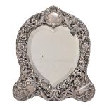 A Victorian heart shaped silver dressing mirror, the die stamped trellis mount decorated with