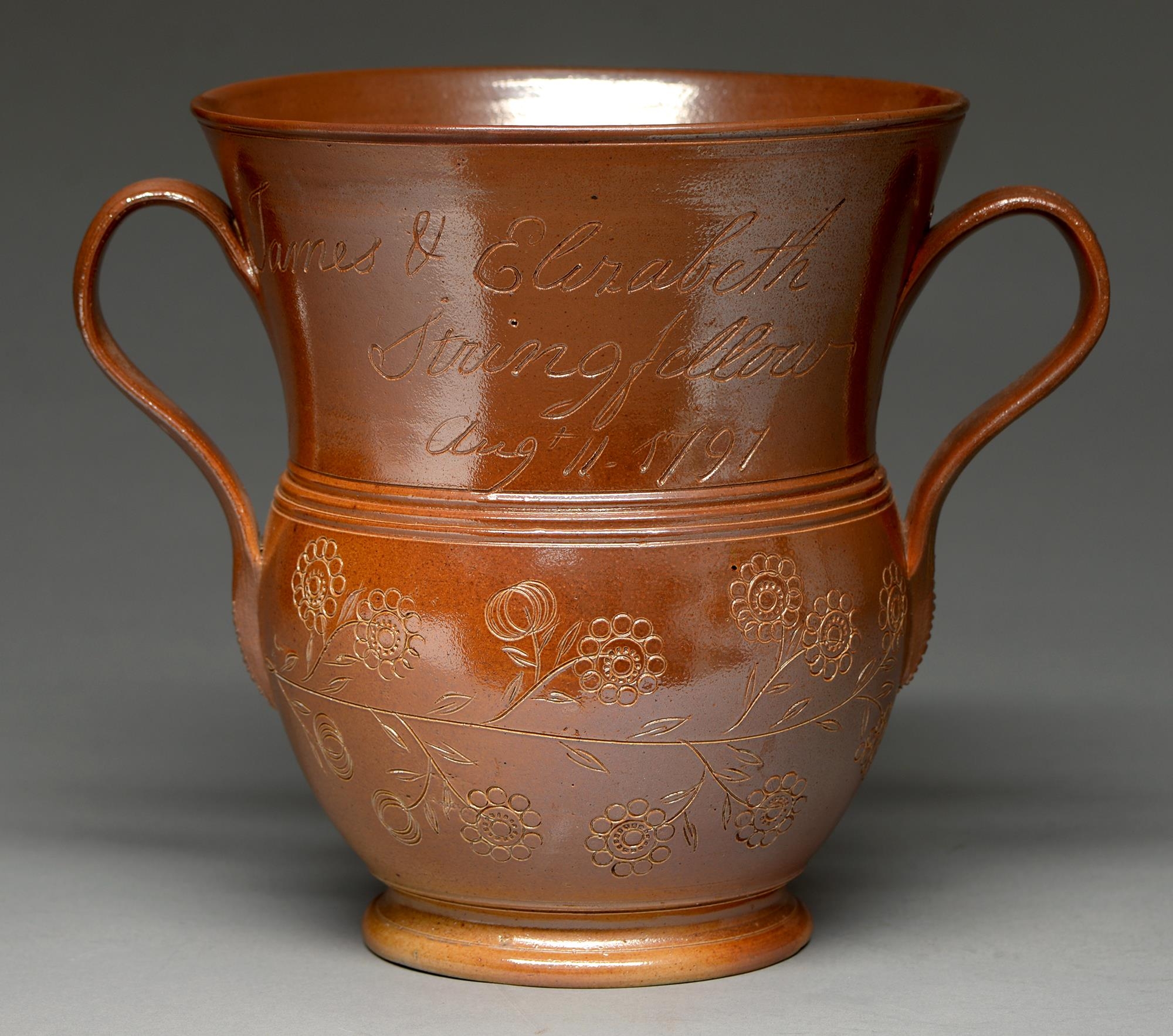 A Derbyshire saltglazed brown stoneware loving cup, Chesterfield, dated 1797, the flared neck