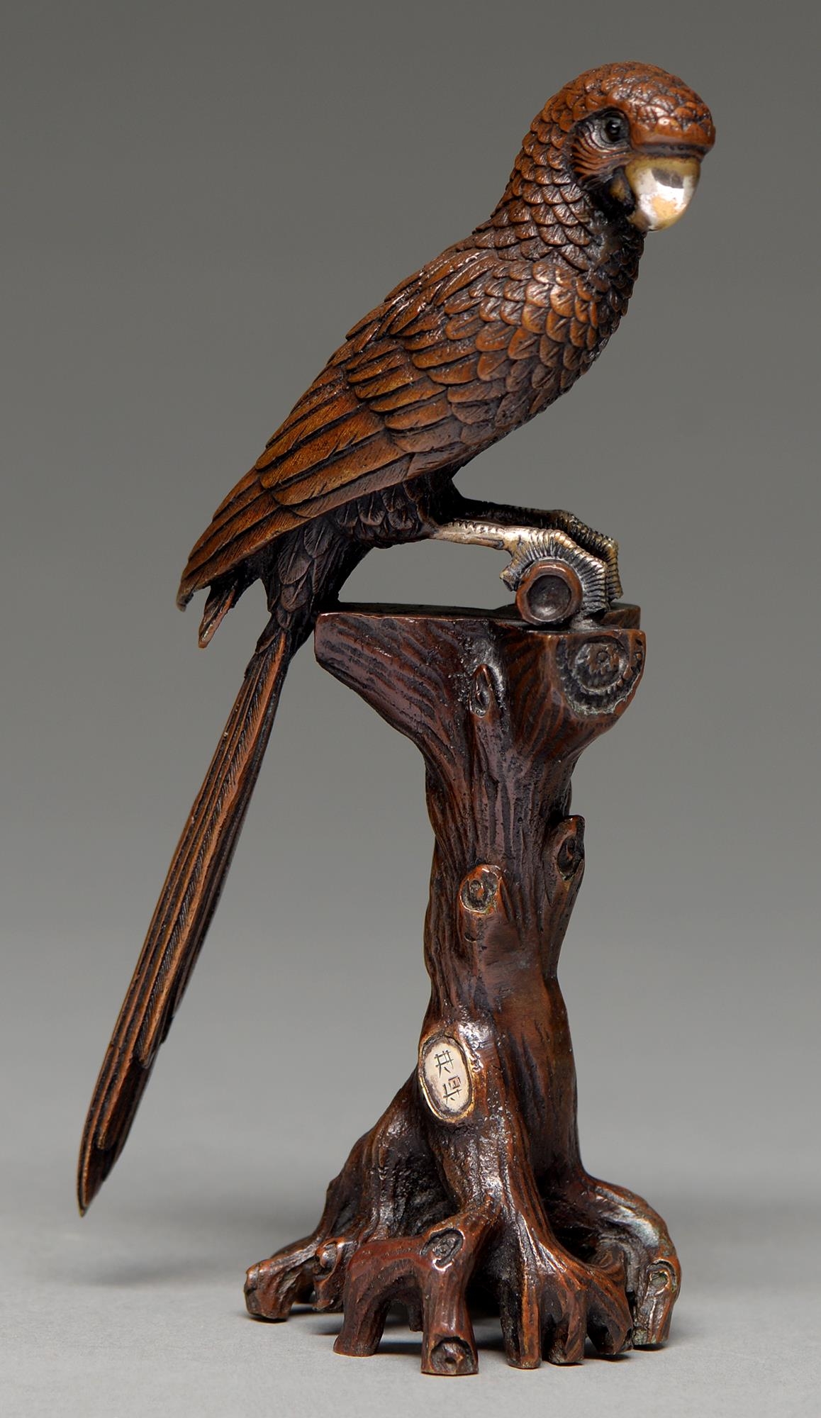 A  bronze and mixed metals okimono of a parrot,   perched on a gnarled tree stump, 19.3cm h,