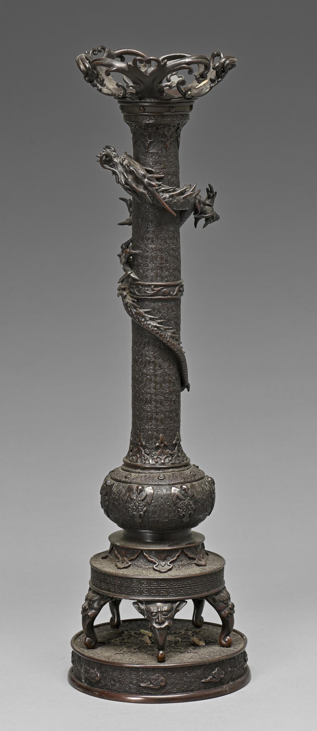 A Japanese bronze candle stand, Meiji period, a dragon entwined around the pillar, the bulbous