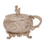 A Burmese silver repousse mustard pot,  late 19th c, chased in high relief with panels of birds