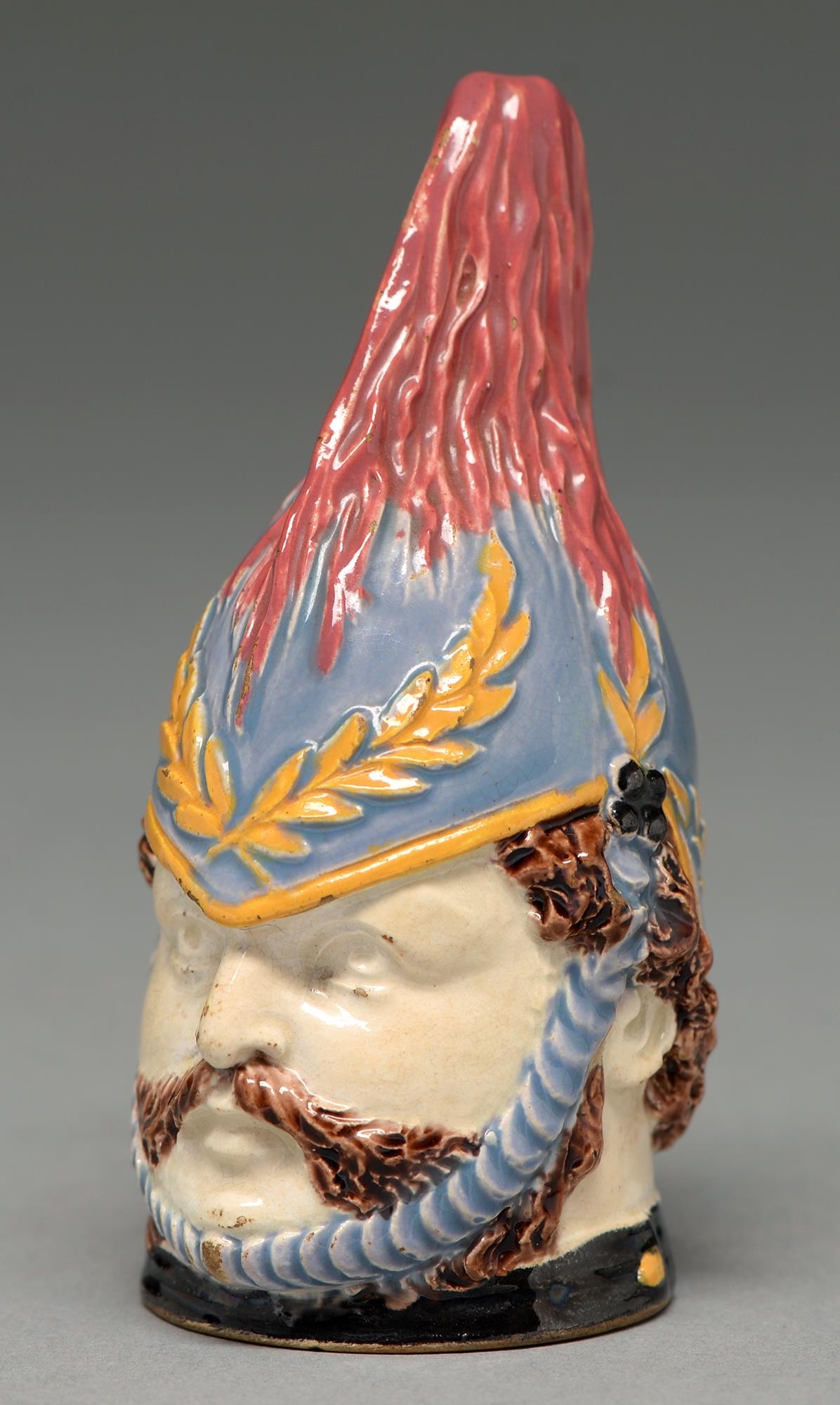 An enamelled creamware candle snuffer in the form of the head of a soldier, 19th c, 95mm h