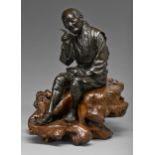 A Japanese bronze sculpture of a man, seated with contemplative expression holding his tobacco