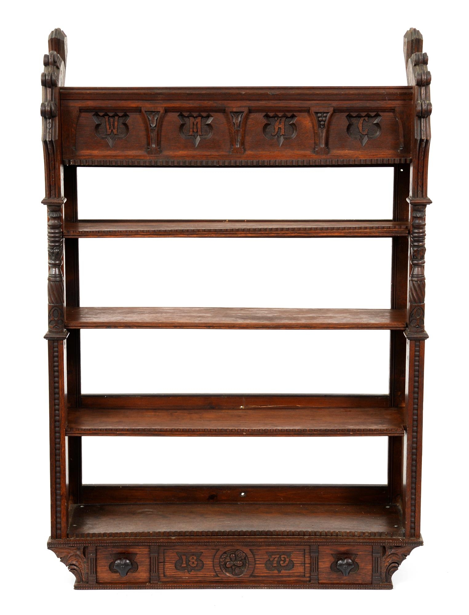 A Victorian reformed gothic oak hanging bookcase, the frieze carved with initials W M A C, the