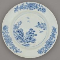 A Chinese blue and white dish, 18th c, painted with a river scene and three trailing peony sprays,