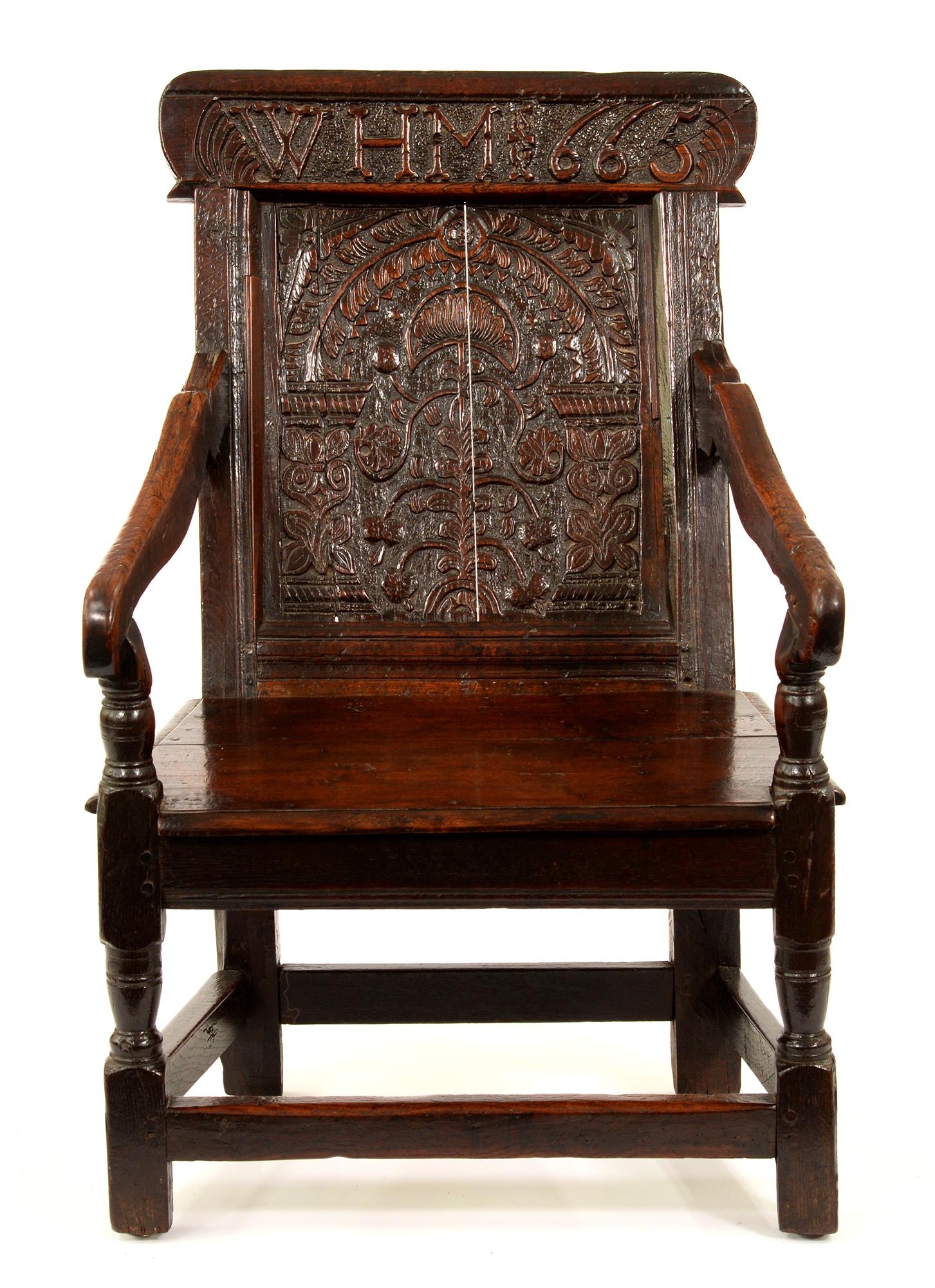 A Charles II oak panel-back armchair, the panel to the back carved with a sunflower and foliage