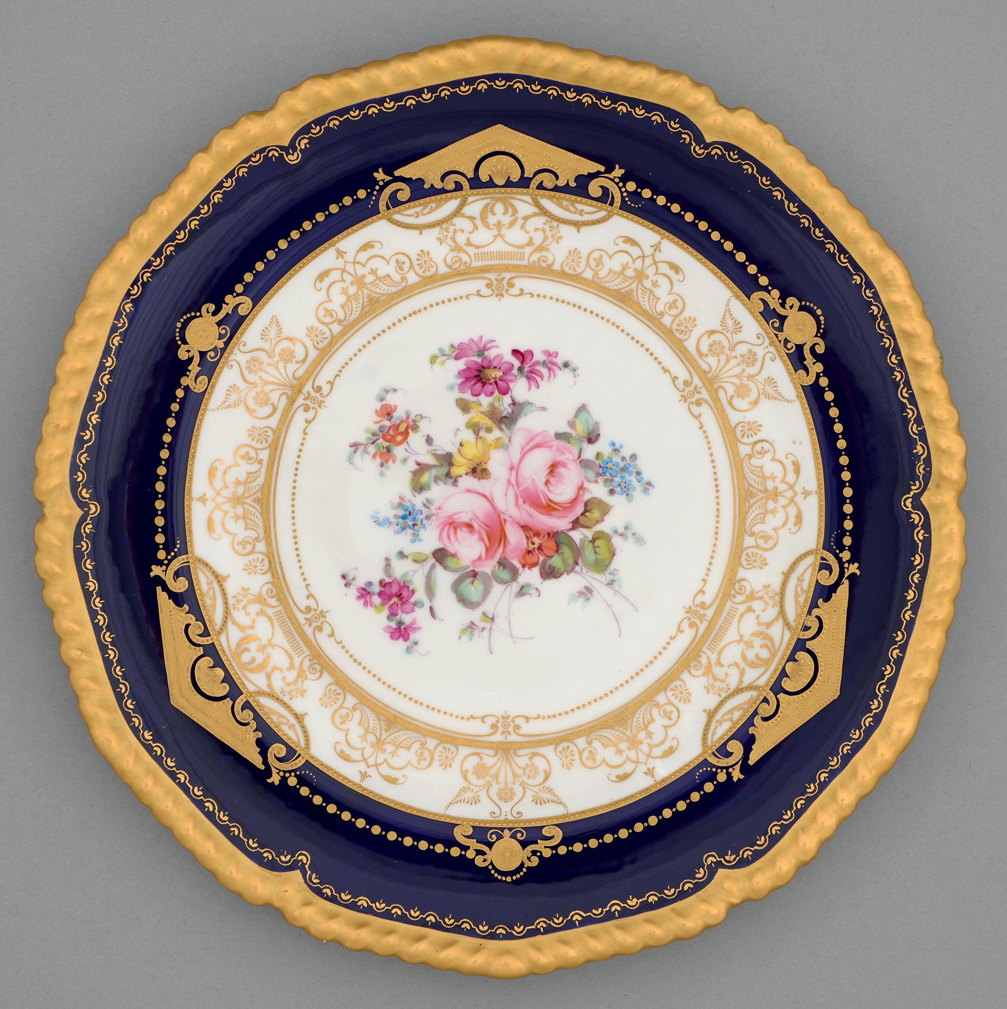 A Royal Crown Derby dessert plate, 1910, painted with flowers in raised gilt surround, cobalt border