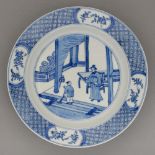 A Chinese blue and white plate, Kangxi period, painted with a figure conversing with a house boy