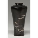 A Japanese bronze vase, Meiji period, carved and inlaid in gold and silver above a surging sea