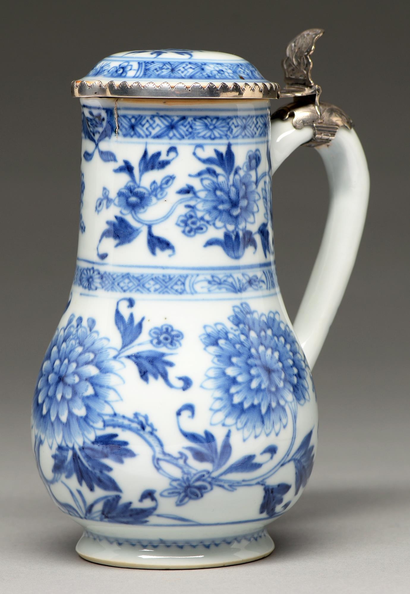 A Chinese blue and white jug, 18th c, painted in two registers with peonies between diaper