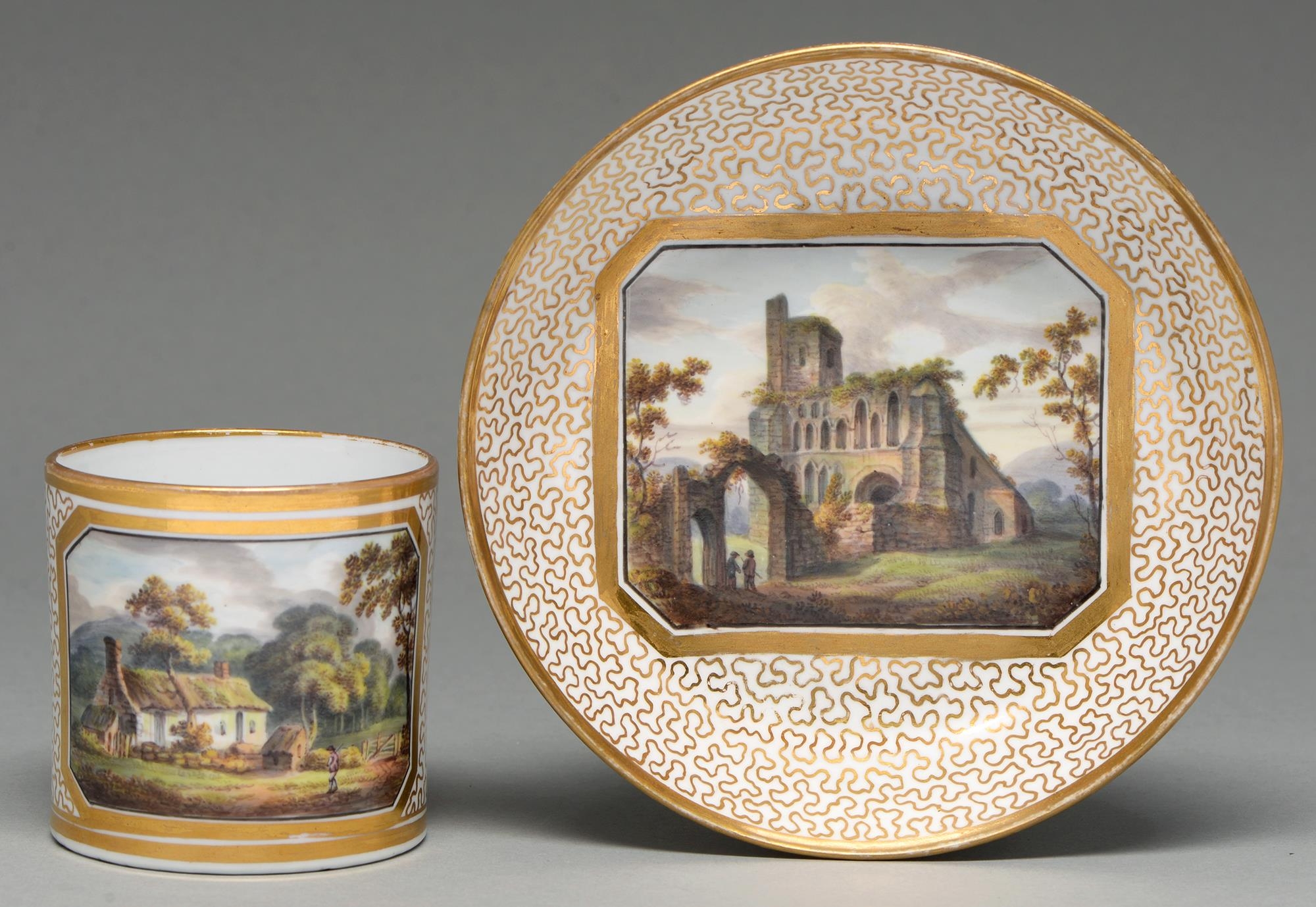 An Herculaneum coffee can and saucer, c1805, painted with a thatched cottage or ruins in gilt