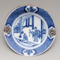 A Chinese blue and white plate, Kangxi period, painted with a lady addressing a house boy, the