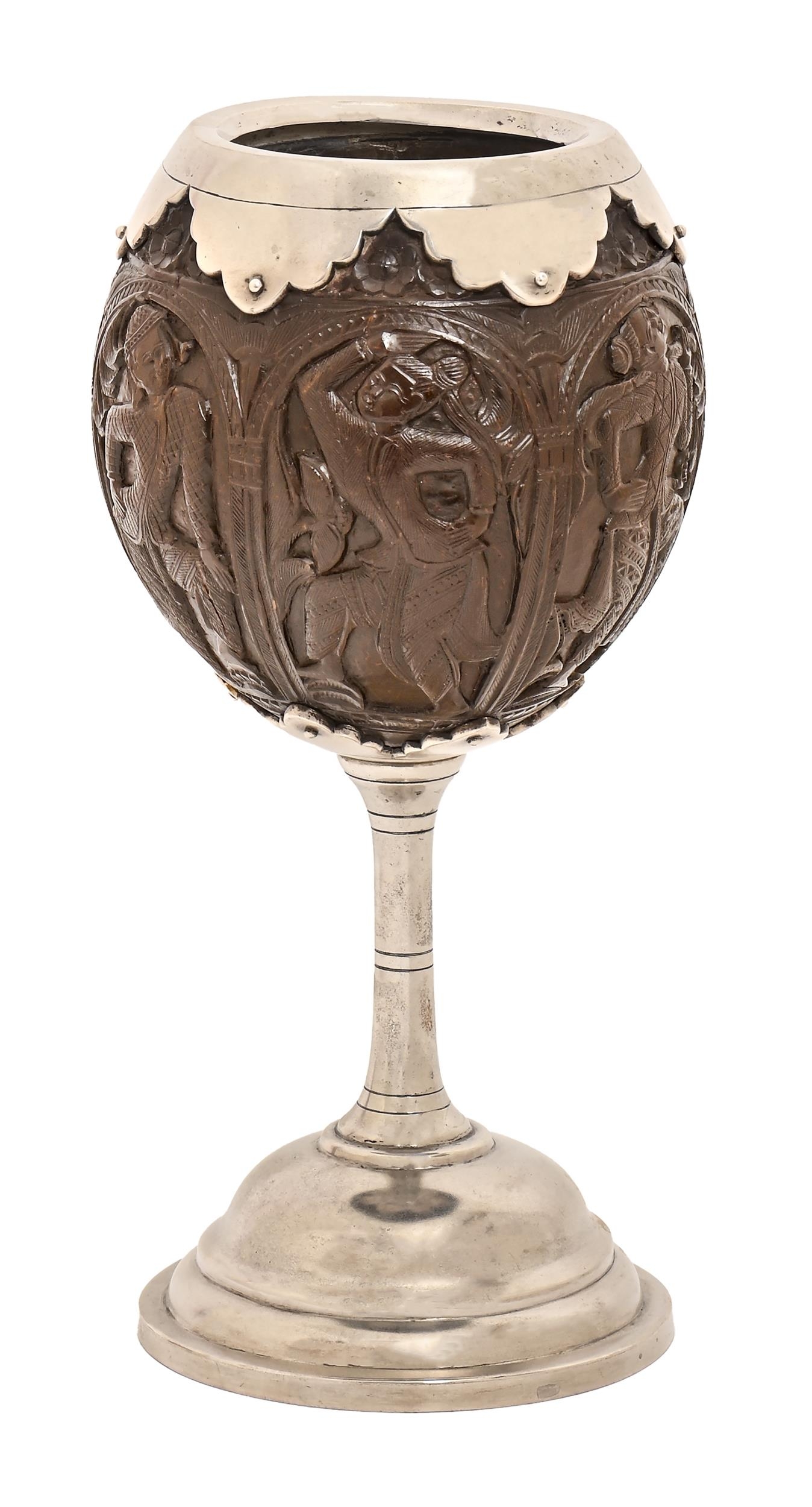 An Indian silver mounted coconut cup, 19th c, carved with six Hindu deities beneath an arch of