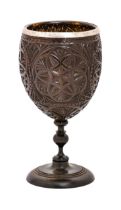 A coconut cup, France, 18th/19th c, carved with geometric patterns on slender turned ebony foot,