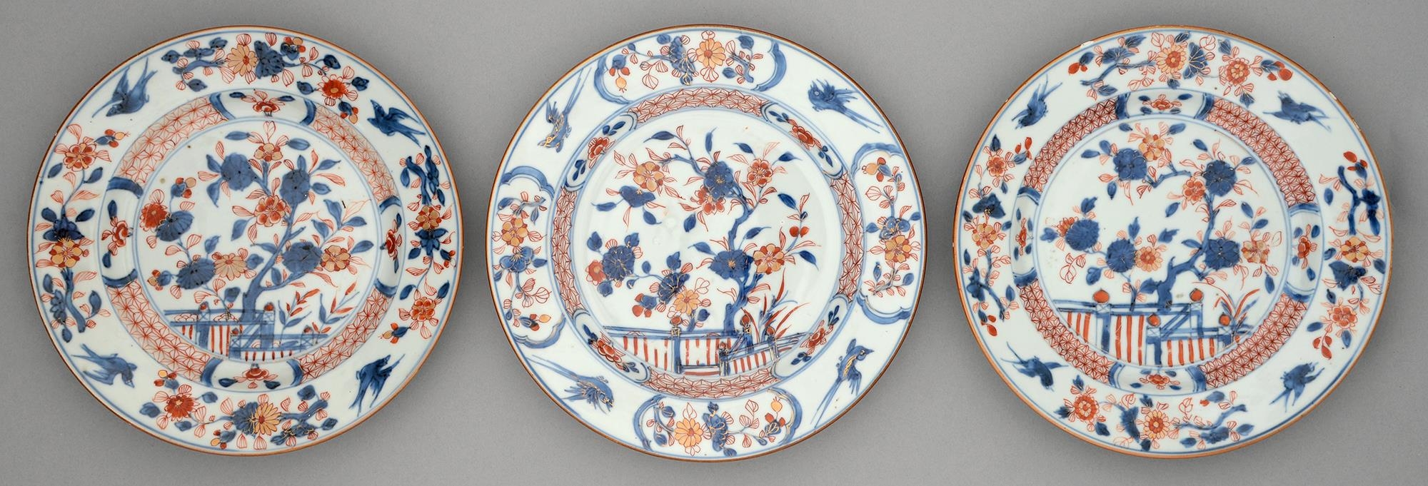 Three Chinese Imari plates, 18th c, painted with a blossoming tree and fence in panelled diaper