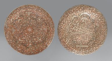 Two brass Cairo ware plates, Egypt or Syria, 19th c, with applied silver decoration, one on three