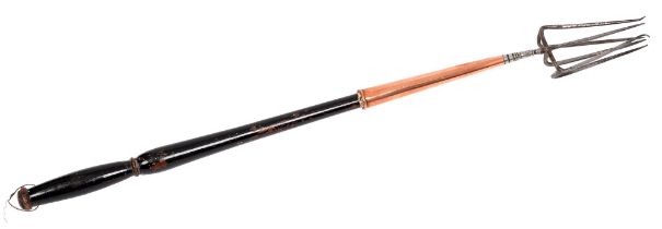 A George III steel six-prong fork, with copper ferrule and turned, ebonised wood handle, 69cm l Wear