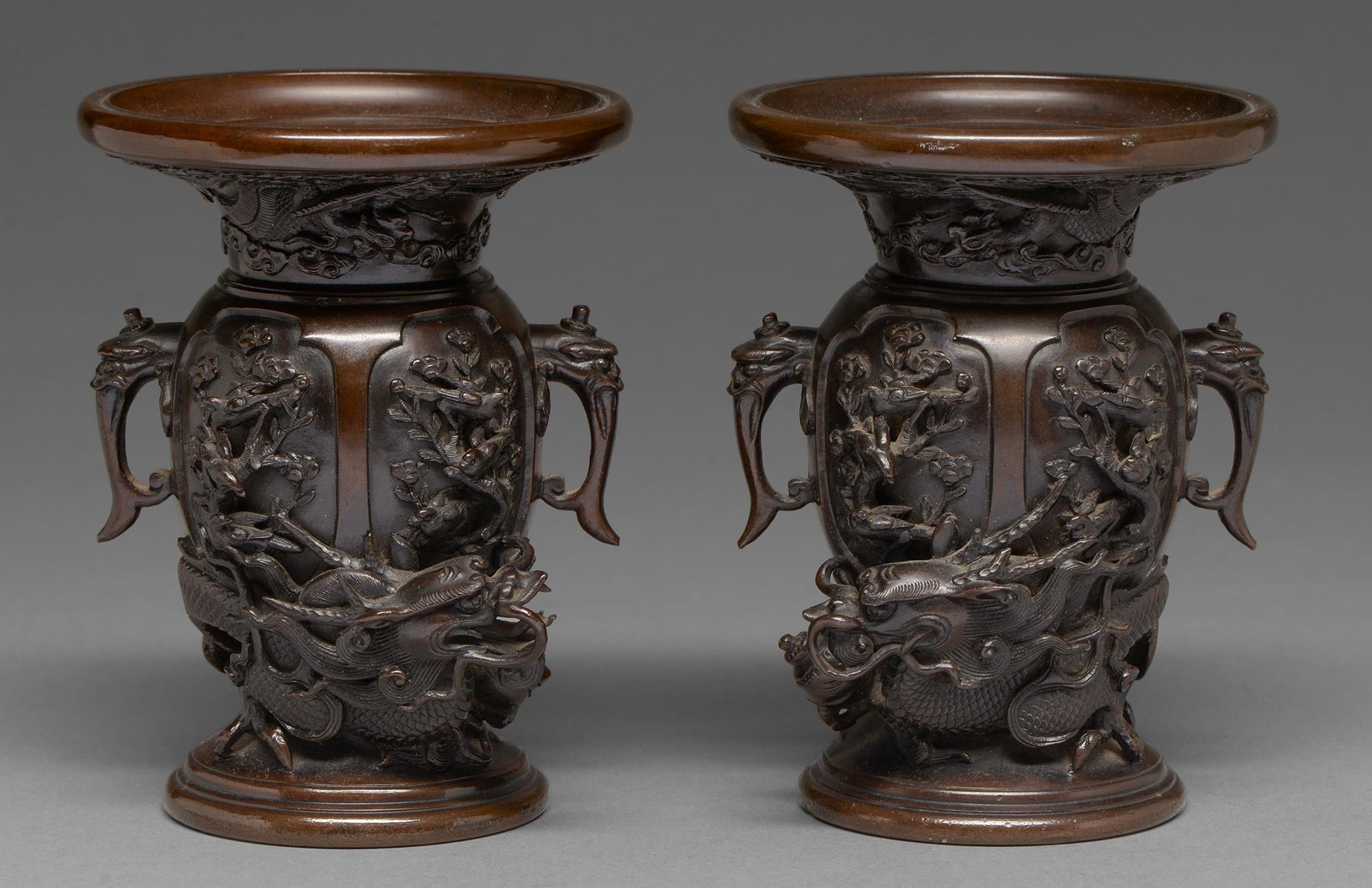 A pair of Japanese bronze dragon and phoenix vases, Meiji period, with high relief cast and