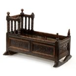 A James II oak cradle, dated 1686, with turned finials and bobbin turned gallery, the panels to