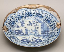 A Chinese blue and white dish, Kangxi period, painted with two figures by a house and hollow