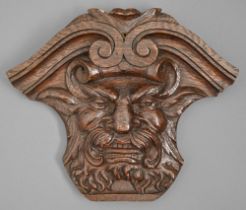 An oak applique, 19th c, in the form of a grotesque mask crested by volutes, 27cm h Small drilled