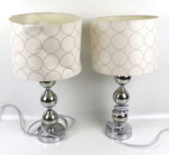A pair of contemporary chrome bobbin like table lamps.