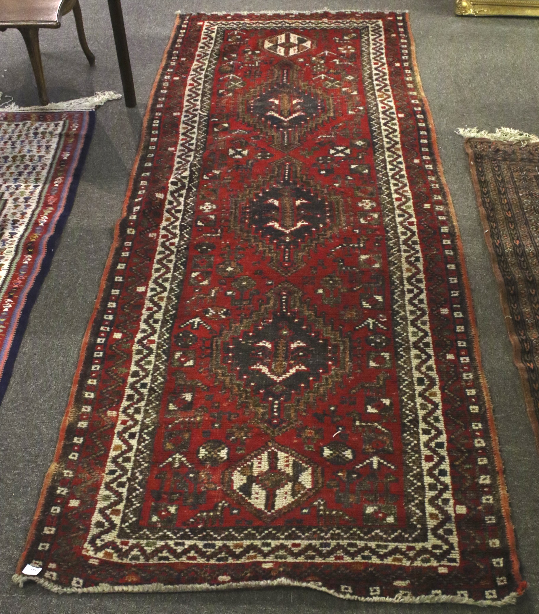 A Kilim style wool rug/ carpet runner. With red ground, geometric border and animal figures.