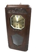 A carved oak cased Art Deco 8 day chiming pendulum wall clock.