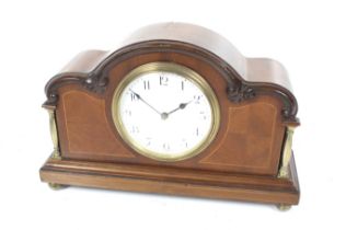 A French mahogany inlaid mantel clock. Brass columns, ball feet and an arched top.