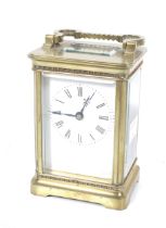 A brass carriage clock. With a white enamel dial and Roman numerals, bevel edge glass panels.