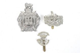A collection of three military cap badges.