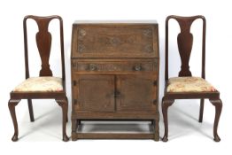 A carved oak bureau and two chairs.