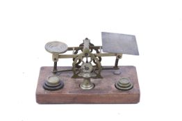 A set of vintage brass postage scales by S Mordan & Co and set of weights, on a wooden base.