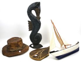 An assortment of wooden sculptural items. Including a loaf of bread placed on a board, a hat, etc.