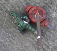 Two vintage hand water pumps. In green and red, with wooden handles.