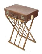 A folding bamboo luggage rack and vintage leather suitcase.