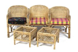 A set of three wicker and bamboo tub chairs and two side tables.