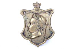 A vintage solid brass wall plaque in the form of a shield.