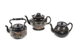 Two Victorian china teapots and a kettle, the black glaze gilded and decorated with flowers.