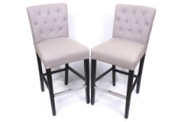A pair of wood framed grey upholstered button back bar stools.