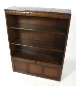 An Ercol freestanding bookcase. With a single door cupboard beneath two adjustable shelves.