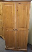 A contemporary pine wardrobe. With twin panelled doors, raised on bracket supports, (AF).
